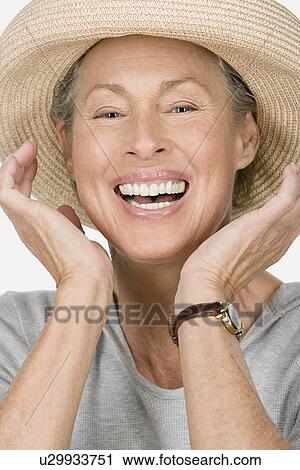 Stock Image - Studio portrait of senior woman wearing hat. Fotosearch