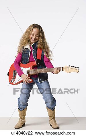 Stock Image - Studio portrait of smiling girl (8-9) playing electric guitar. Fotosearch