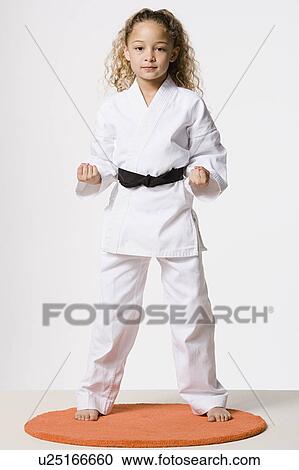 Stock Image - Studio portrait of smiling girl (8-9) wearing gi. Fotosearch