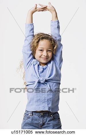 Stock Photography - Studio portrait of smiling girl (8-9) with arms up. Fotosearch
