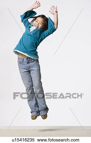 Stock Photography - Studio portrait of smiling girl (8-9) jumping. Fotosearch