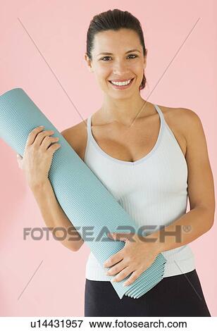 Stock Photo - Studio portrait of woman holding exercise mat. Fotosearch