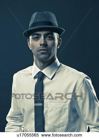 Stock Photography - Studio portrait of young man wearing tie and hat. Fotosearch