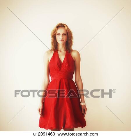 Stock Image - Studio portrait of young woman in red dress. Fotosearch