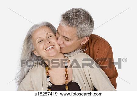Stock Photo - Studio shot of mature man kissing woman. Fotosearch