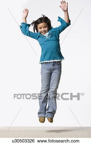 Stock Photograph - Studio shot of smiling girl (8-9) jumping. Fotosearch
