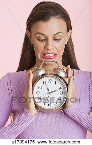 Studio shot of woman holding alarm clock View Large Photo Image Stock Photography - Studio shot of woman holding alarm clock. Fotosearch