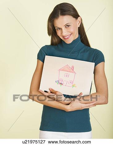 Stock Photo - Studio shot of woman holding drawing depicting house. Fotosearch