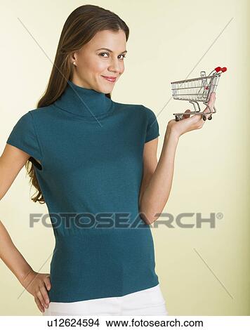 Picture - Studio shot of woman holding small shopping cart. Fotosearch