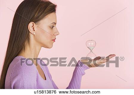 Stock Photograph - Studio shot of woman holding small hourglass. Fotosearch