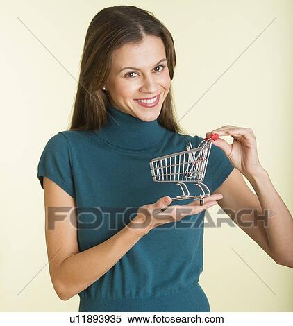 Studio shot of woman holding small shopping cart View Large Photo Image Stock Photography - Studio shot of woman holding small shopping cart. Fotosearch