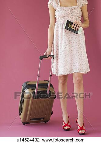 Studio shot of woman holding suitcase and passport View Large Photo Image Stock Image - Studio shot of woman holding suitcase and passport. Fotosearch