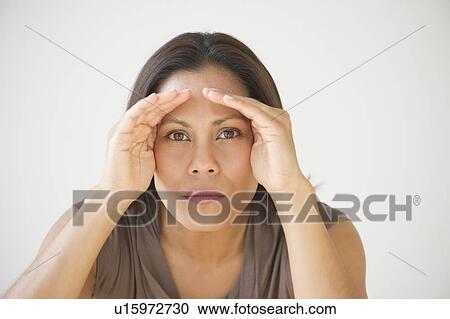 Stock Image - Studio shot of woman shielding eyes. Fotosearch
