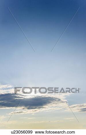 Stock Photo - Sun covered with clouds on blue sky. Fotosearch
