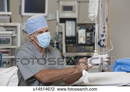 Stock Image - Surgeon putting on gloves. Fotosearch