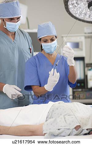 Picture - Surgeons preparing patient for surgery. Fotosearch
