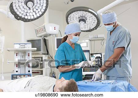 Stock Image - Surgeons preparing patient for surgery. Fotosearch
