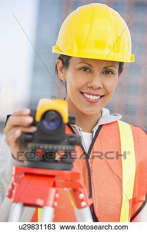 Stock Image - Surveyor using a theodolite instrument. Fotosearch