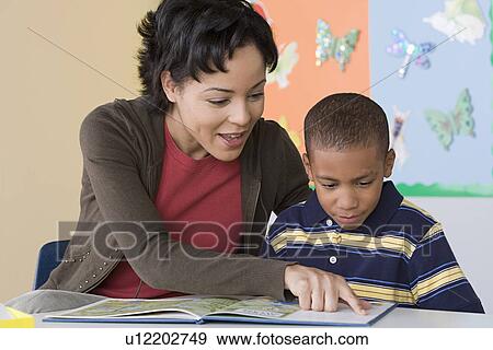 Teacher helping boy (6-7) in reading View Large Photo Image Stock Photo - Teacher helping boy (6-7) in reading. Fotosearch