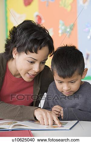 Teacher helping boy (6-7) to read View Large Photo Image Stock Image - Teacher helping boy (6-7) to read. Fotosearch