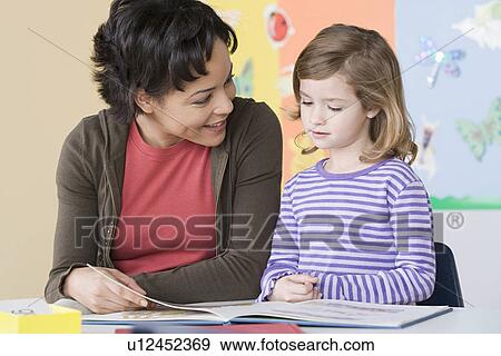 Teacher helping girl (6-7) in reading View Large Photo Image Stock Photo - Teacher helping girl (6-7) in reading. Fotosearch