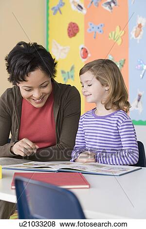 Teacher helping girl (6-7) in reading View Large Photo Image Stock Photo - Teacher helping girl (6-7) in reading. Fotosearch