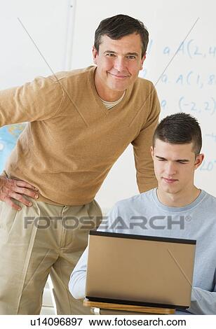 Stock Photo - Teacher helping teenage (16-17) student . Fotosearch