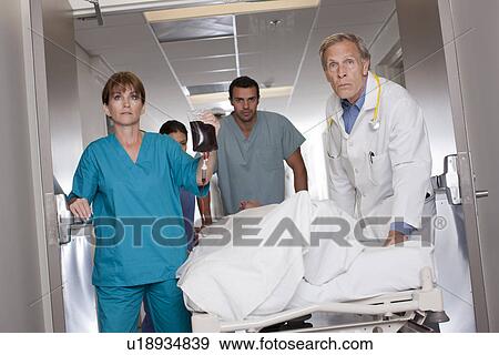 Team of doctors wheeling in patient View Large Photo Image Stock Photo - Team of doctors wheeling in patient. Fotosearch
