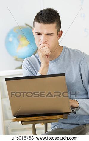 Stock Image - Teenage (16-17) student using laptop. Fotosearch