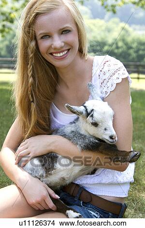 Picture - Teenage girl (14-15) holding small goat. Fotosearch