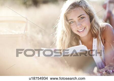 Teenage girl (16-17) posing for portrait while reading book outdoors View Large Photo Image Picture - Teenage girl (16-17) posing for portrait while reading book outdoors. Fotosearch