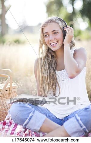Teenage girl (16-17) posing with book and headphones on View Large Photo Image Picture - Teenage girl (16-17) posing with book and headphones on. Fotosearch