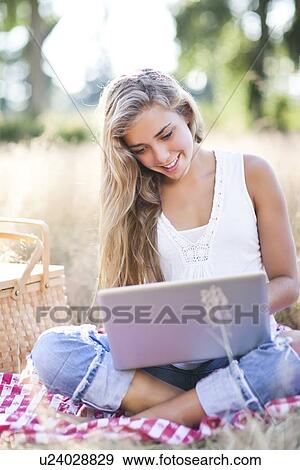 Stock Photo - Teenage girl (16-17) using laptop outdoors. Fotosearch
