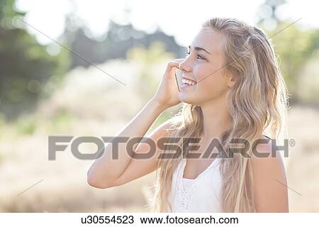 Stock Image - Teenage girl (16-17) using mobile phone outdoors. Fotosearch