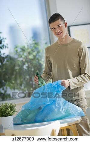 Stock Photo - Teenager (16-17) recycling bottles. Fotosearch