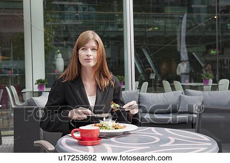 Stock Image - The Netherlands, Amsterdam, Businesswoman eating salad in sidewalk cafe. Fotosearch