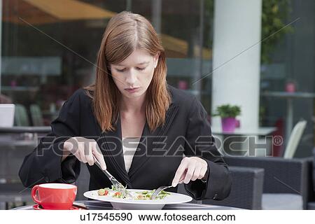 Stock Image - The Netherlands, Amsterdam, Businesswoman eating salad in sidewalk cafe. Fotosearch