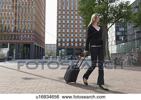 The Netherlands, Amsterdam, Businesswoman walking with luggage View Large Photo Image Stock Photograph - The Netherlands, Amsterdam, Businesswoman walking with luggage. Fotosearch