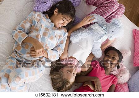 Three girls (10-11) lying on bed at slumber party View Large Photo Image Stock Image - Three girls (10-11) lying on bed at slumber party. Fotosearch
