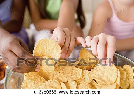 Three girls (10-11) reaching for crisps View Large Photo Image Stock Photograph - Three girls (10-11) reaching for crisps. Fotosearch
