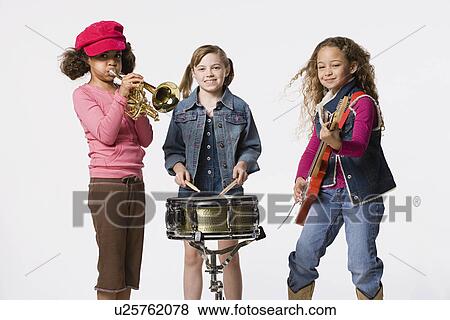 Stock Photo - Three girls (8-9) playing instruments together, studio shot. Fotosearch