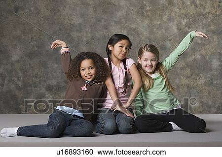 Stock Image - Three girls (8-9) posing, studio shot. Fotosearch