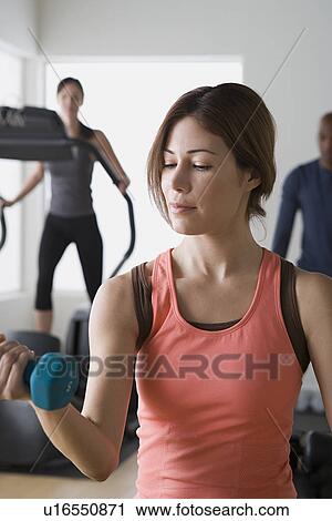 Stock Image - Three people exercising in gym. Fotosearch