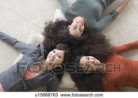 Stock Image - Three women lying on floor. Fotosearch