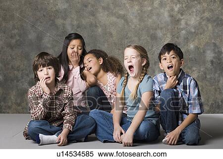 Stock Photography - Tired children (6-7, 8-9) lying together, studio shot. Fotosearch