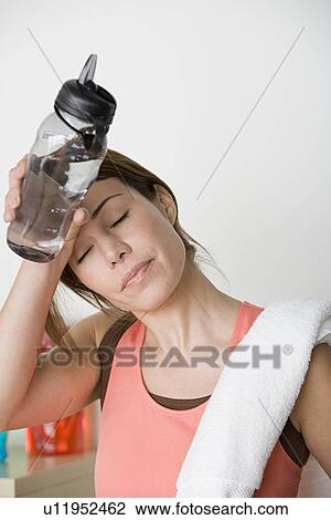Stock Image - Tired female athlete wiping out sweat from forehead. Fotosearch