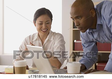 Stock Photography - Two business people working in office. Fotosearch
