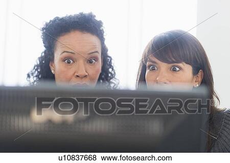 Two business women behind computer looking frightened View Large Photo Image Stock Photo - Two business women behind computer looking frightened. Fotosearch