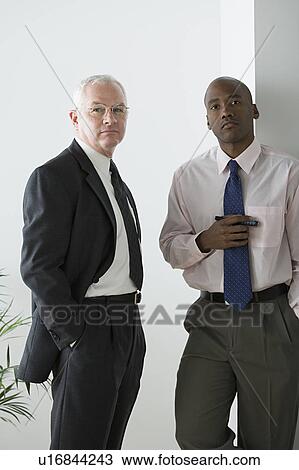 Two businessmen standing in office View Large Photo Image Stock Image - Two businessmen standing in office. Fotosearch