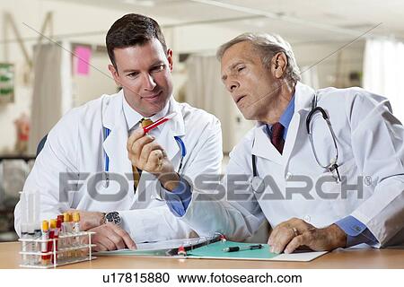 Stock Image - Two doctors examining test tube in hospital. Fotosearch